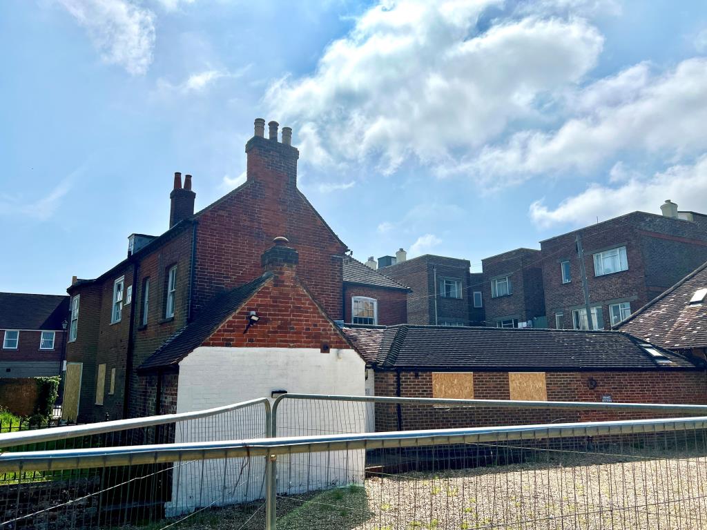 Lot: 40 - LANDMARK FREEHOLD BUILDING WITH PLANNING FOR REDEVELOPMENT - Rear elevation showing brickwork and windows with temporary fencing